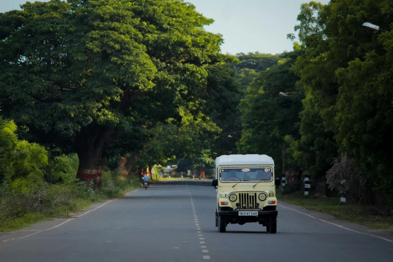 the small yellow truck is traveling down the road