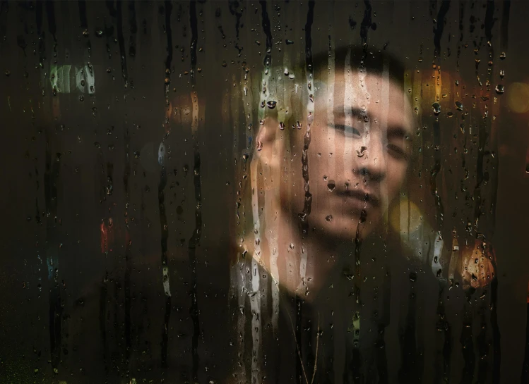 a man is shown behind a curtain of rain