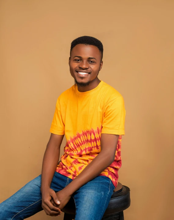 a man smiles while sitting on top of a tire