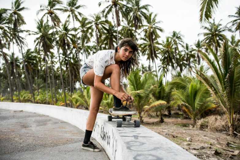 a young woman riding a skateboard along a stone wall