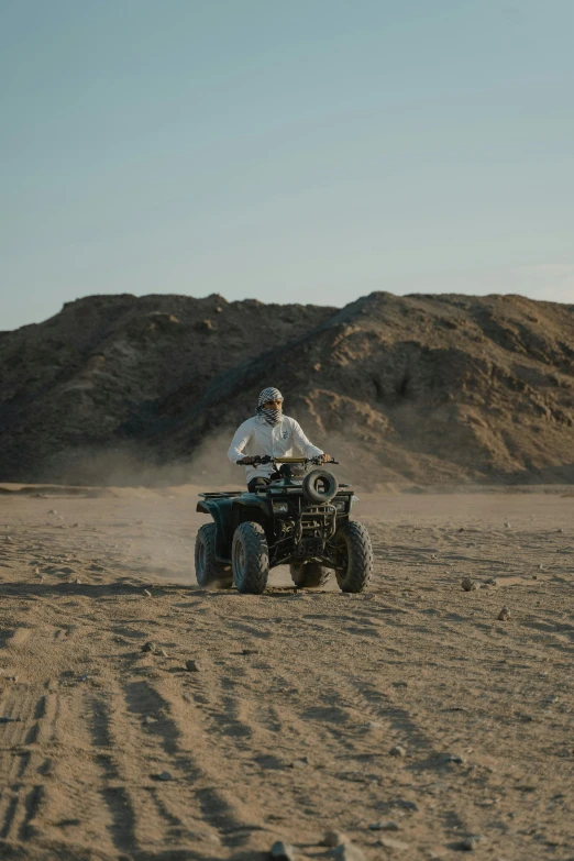 the person is riding on the quad on the beach