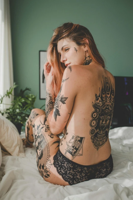 a tattooed woman sitting on a bed