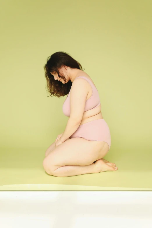 a pregnant woman sitting on a floor in her diaper