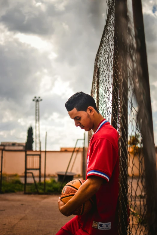 a man holding a ball is in front of a fence