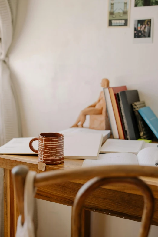 a coffee mug sits on a desk next to books