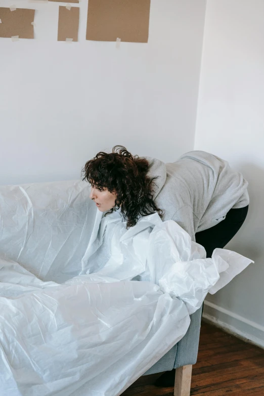 a young woman is under a white sheet on a couch