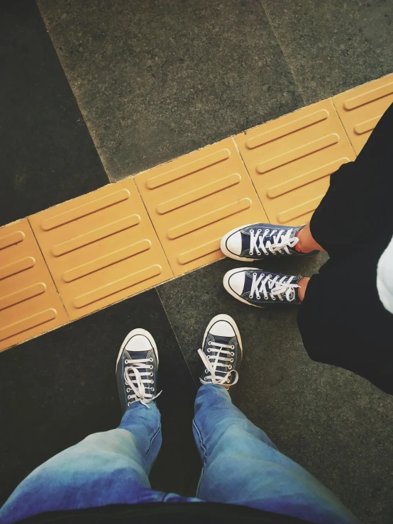 a person wearing black converse shoes next to another person