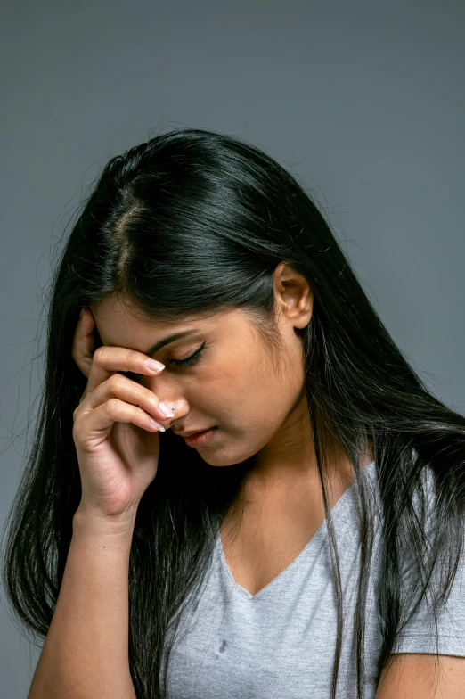 a woman looks thoughtful as she is holding her hands to her forehead