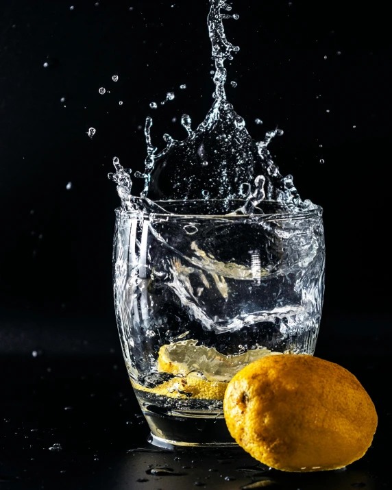 a small lemon sitting next to a glass of water