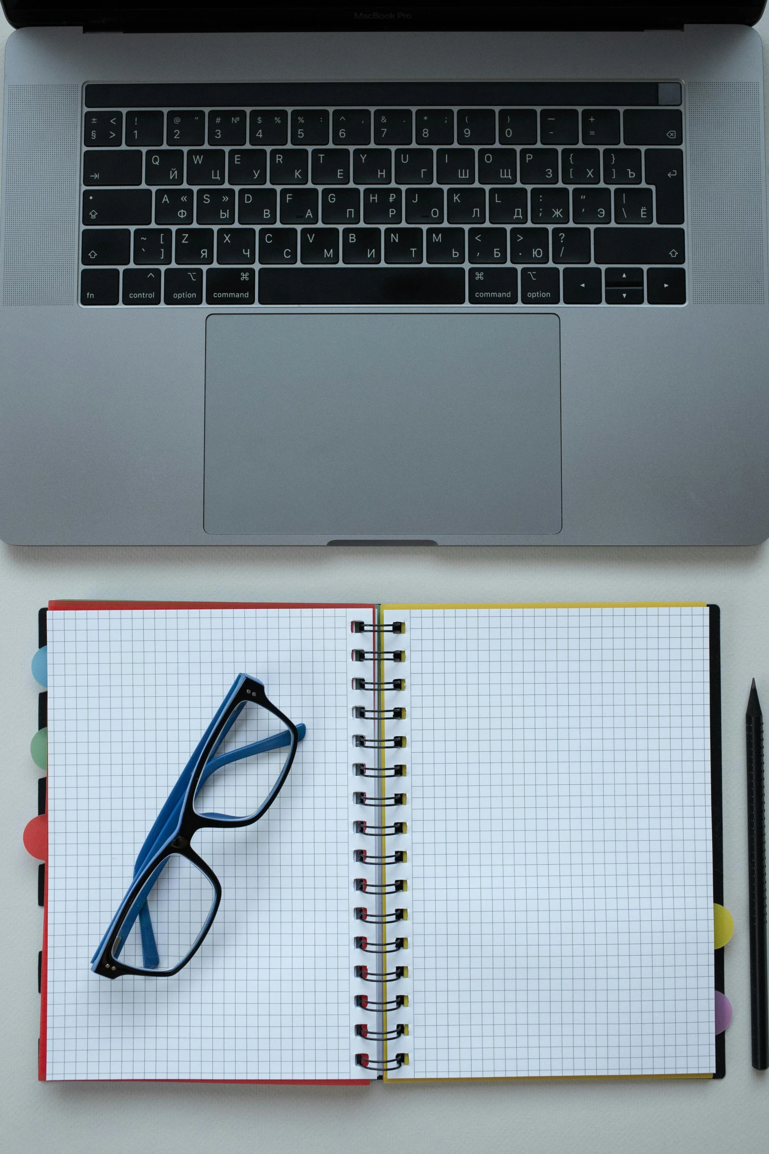 two laptops next to a notebook with blue glasses