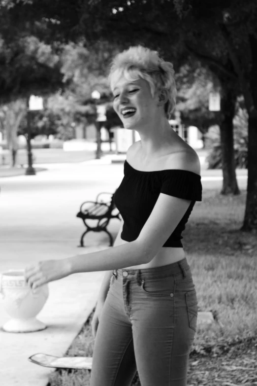 a woman laughing in front of a bench near a sidewalk