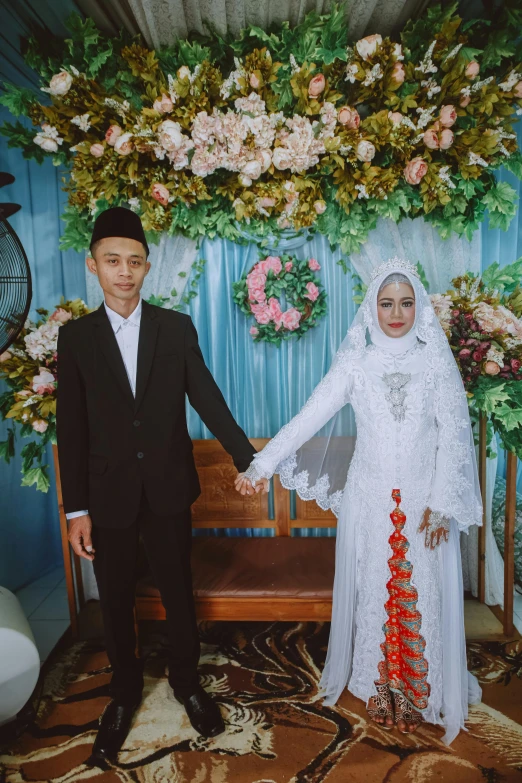 a bride and groom standing in front of a floral wall with flowers