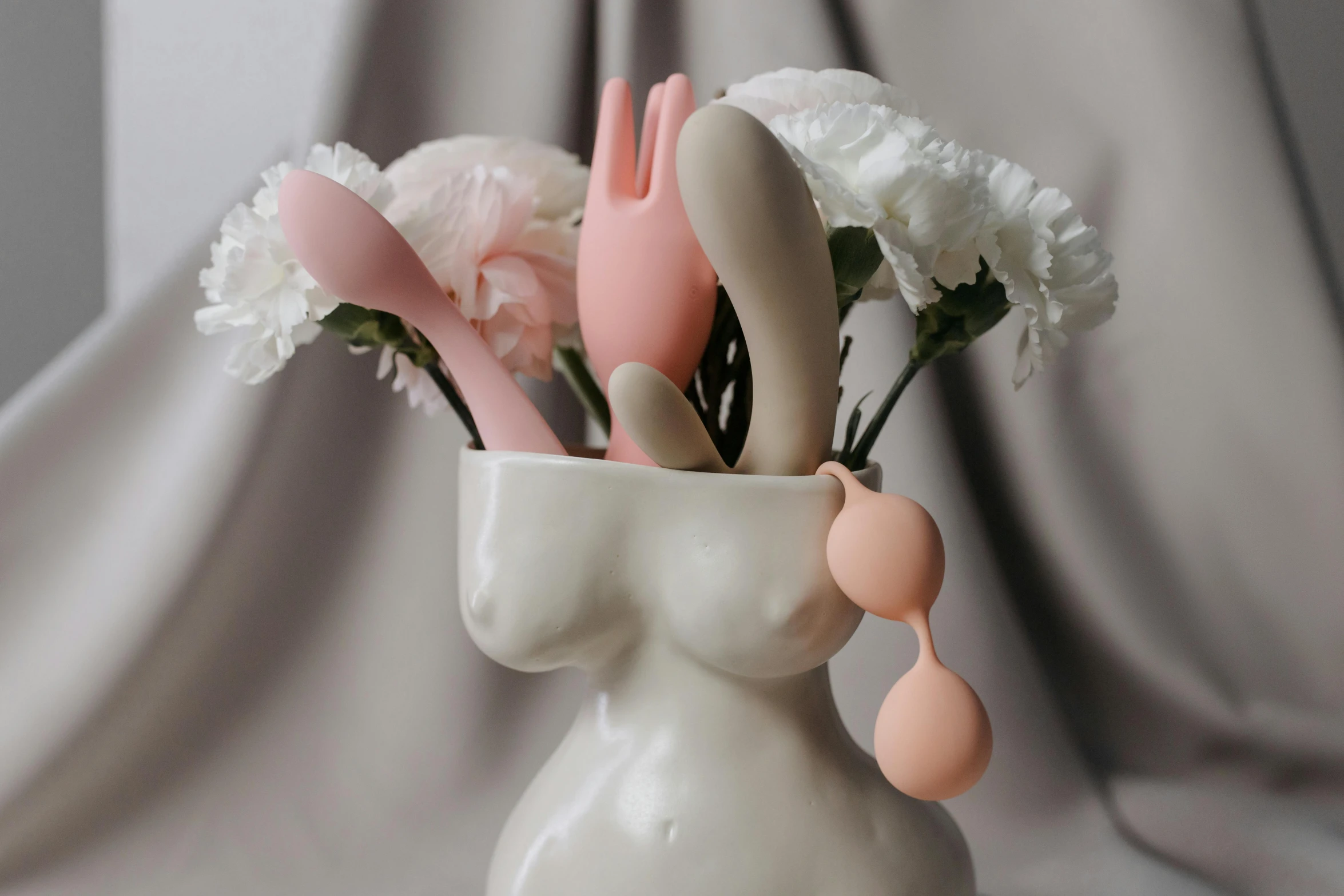 a vase filled with pink and white utensils