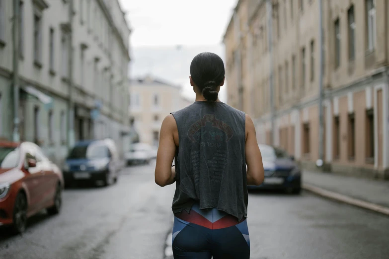 a woman walks in front of parked cars on the road