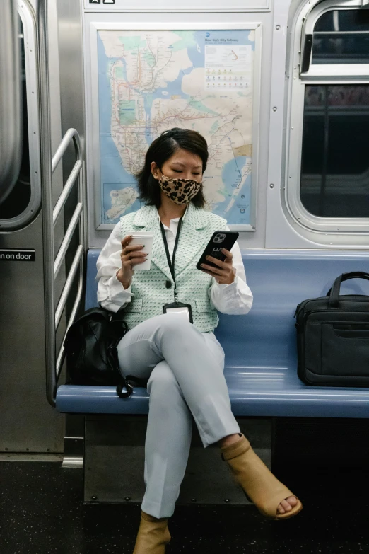 a person on a subway wearing a mask and holding a phone