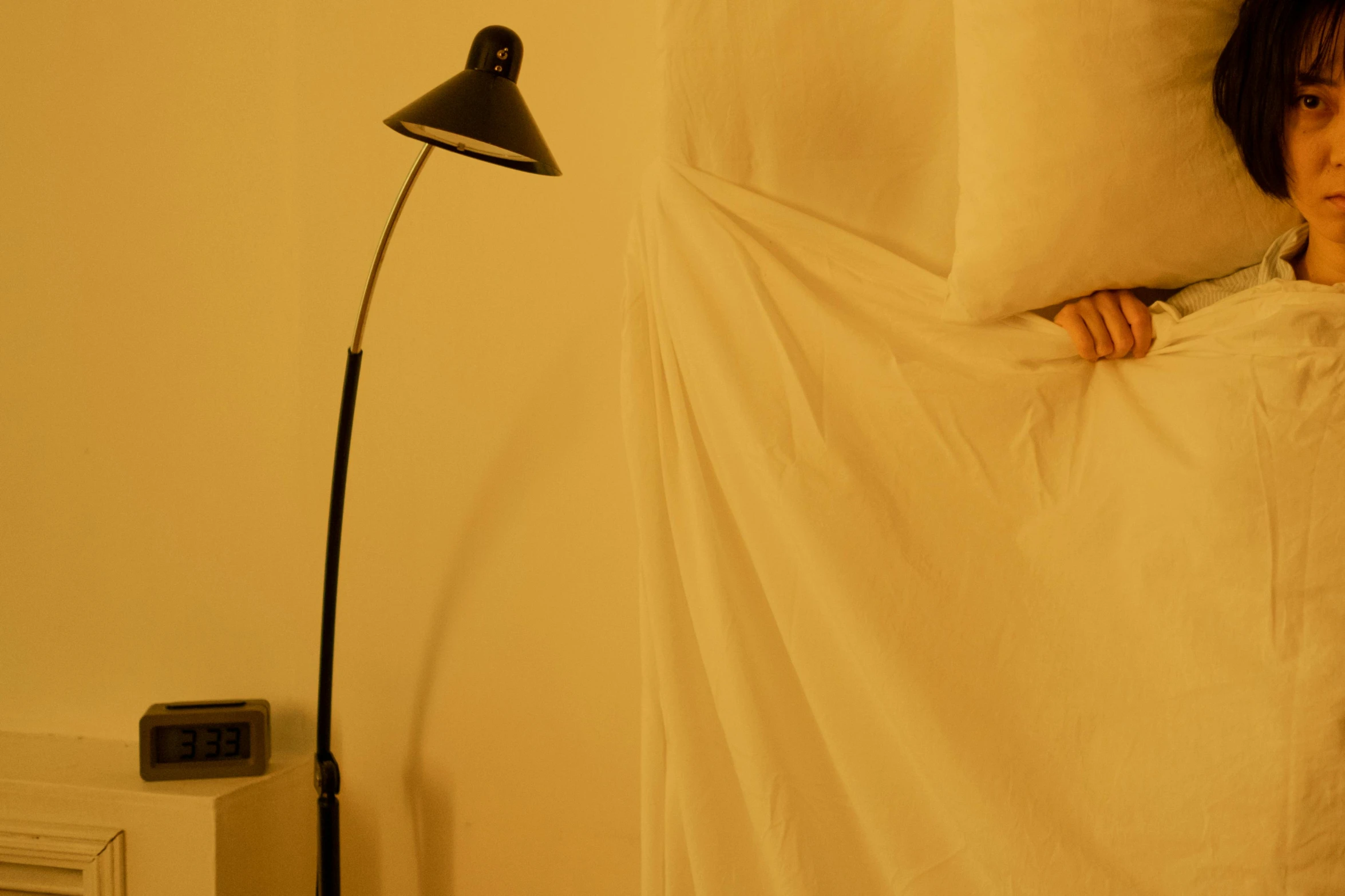 young woman hiding behind sheets in bed