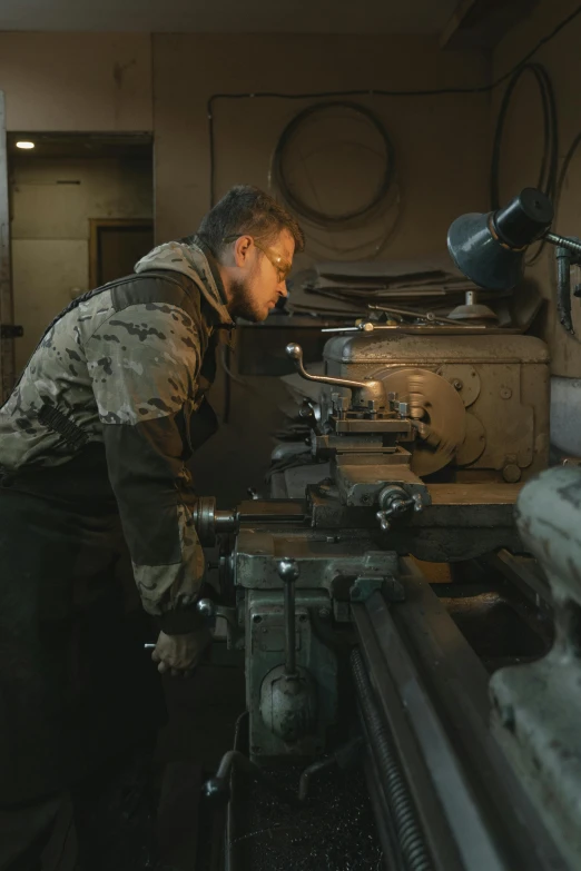 a man standing at a grinder making a piece of metal