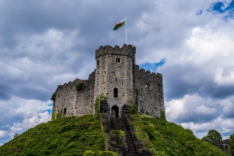 a castle sits on top of a green hill