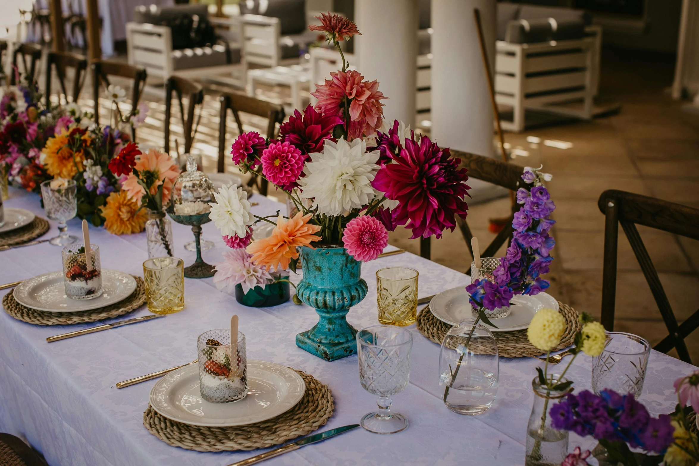 a table has a white cloth with many place settings