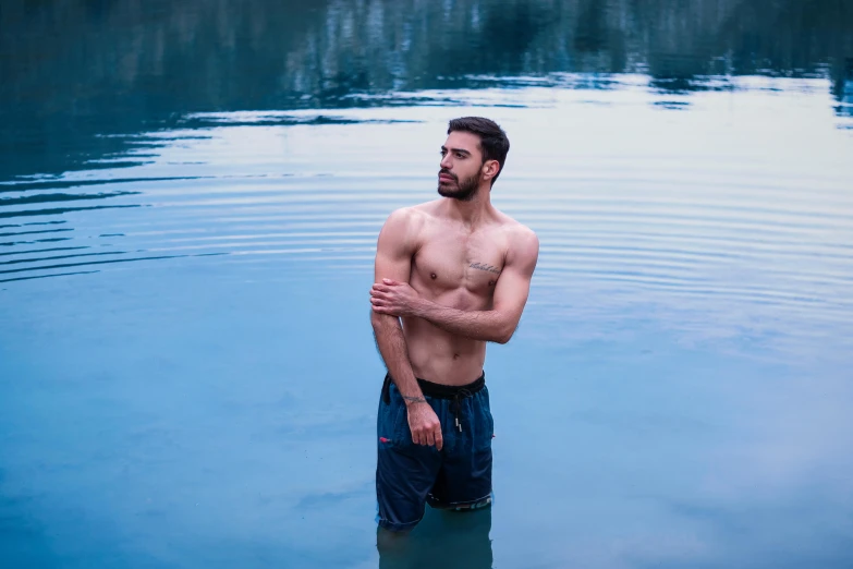 a shirtless man standing in the water in his underwear