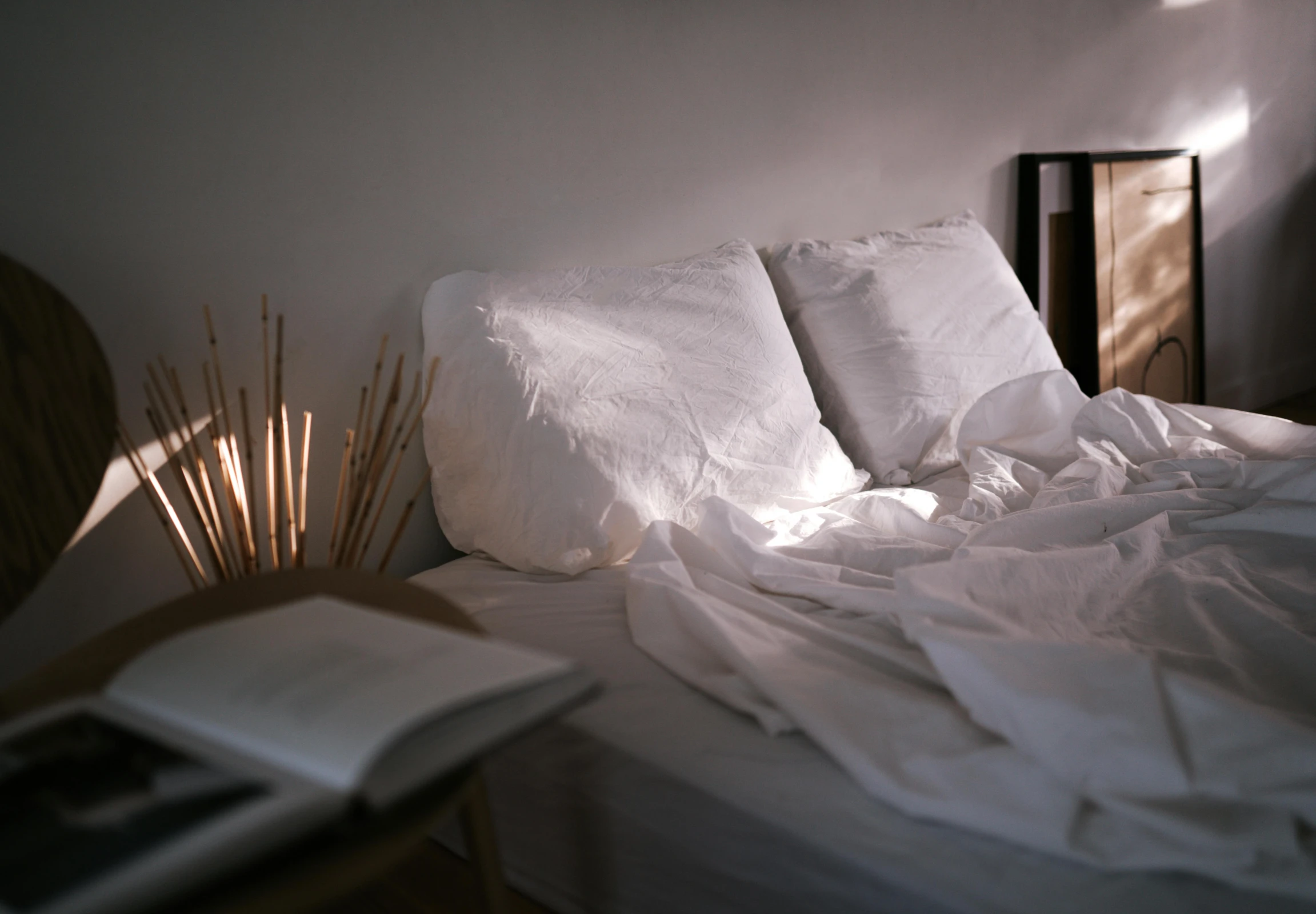 a bed with pillows, pillows and a book on it