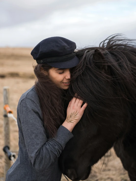 a woman petting the face of a pony