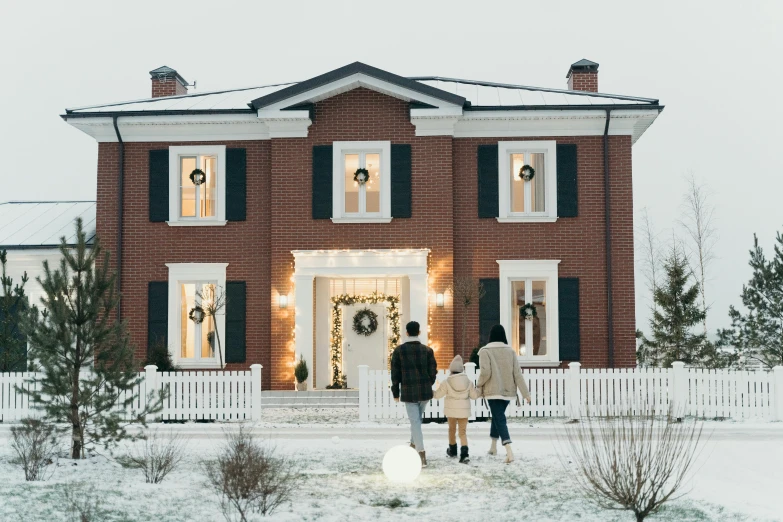 two people walk through the snow near a house