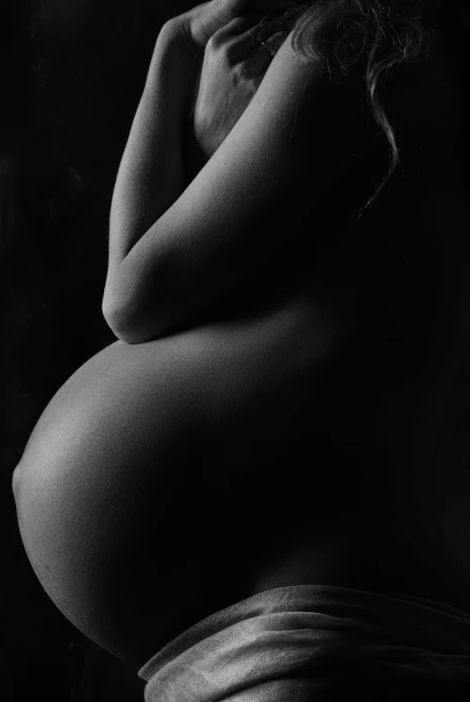 a black and white po of a pregnant woman in a dark room
