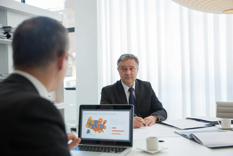 a man sitting at a table with two laptops