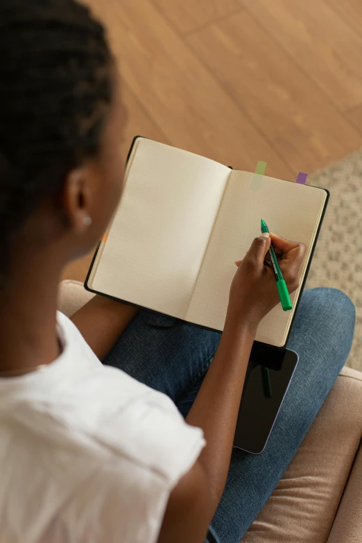 a  writing on a notebook while sitting in front of a dog