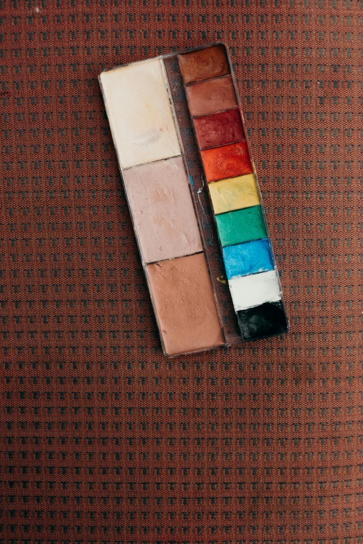 a piece of cloth with a box of paint sitting next to it