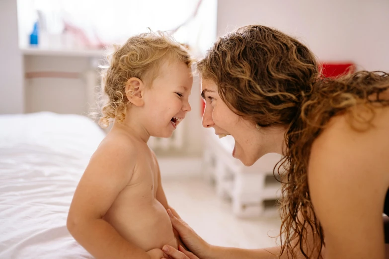 woman and a toddler laughing on a bed