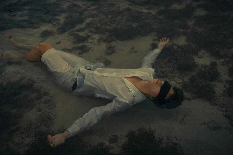 a person in a white shirt and black tie laying on the ground