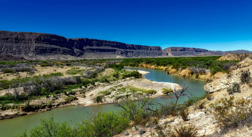 a river flows through a desert landscape near mountains