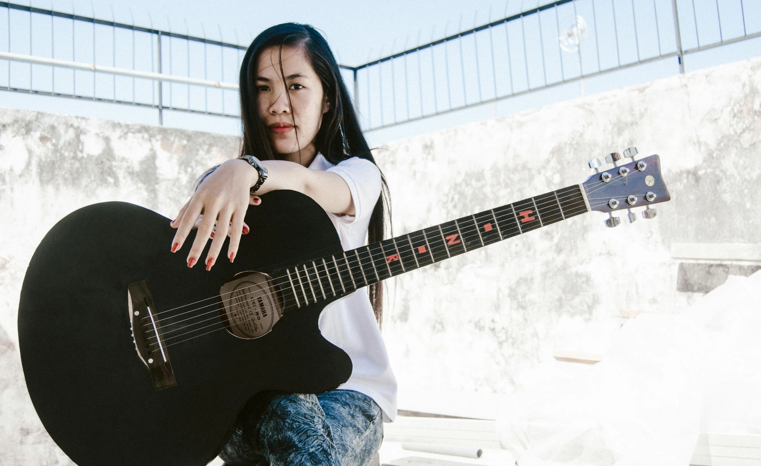 a girl poses with her acoustic guitar, holding it in her hands