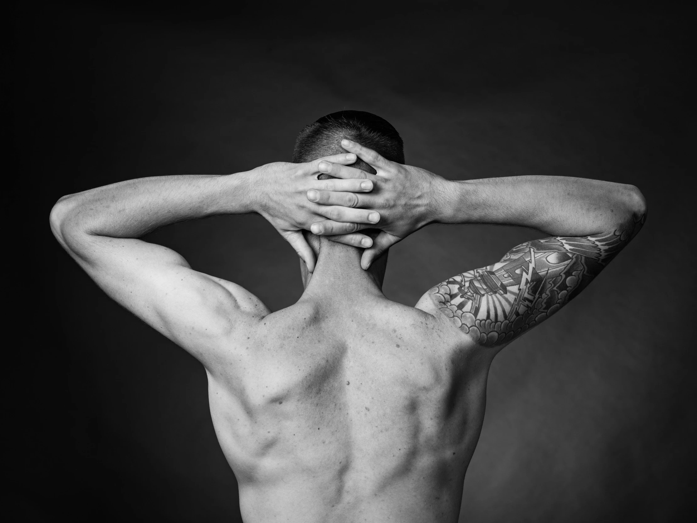 a black and white pograph of a man without shirt showing his tattoos