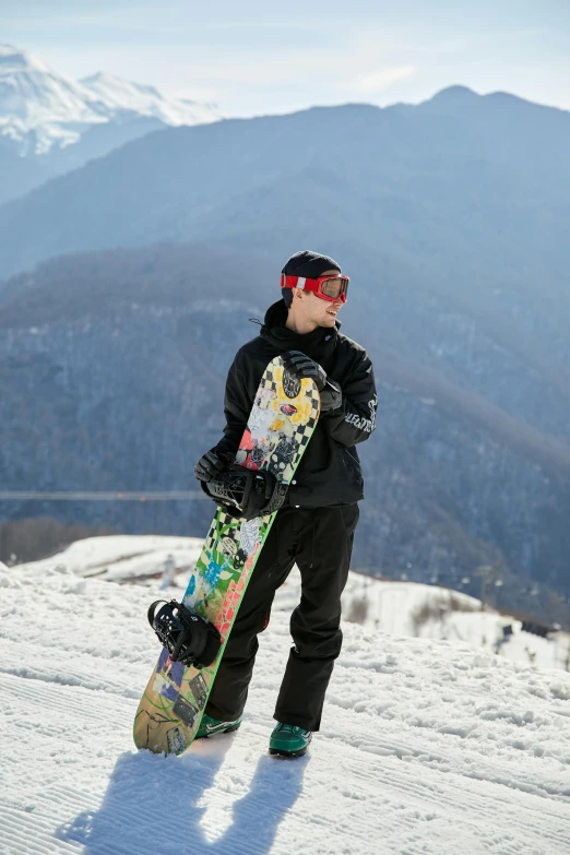 a man holding a snowboard standing on a snowy hillside