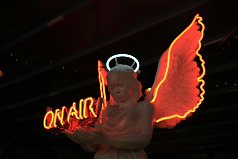 a angel statue standing holding neon lights
