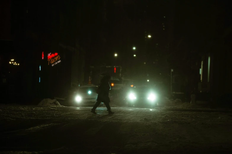 people crossing street at night time by car with headlights on