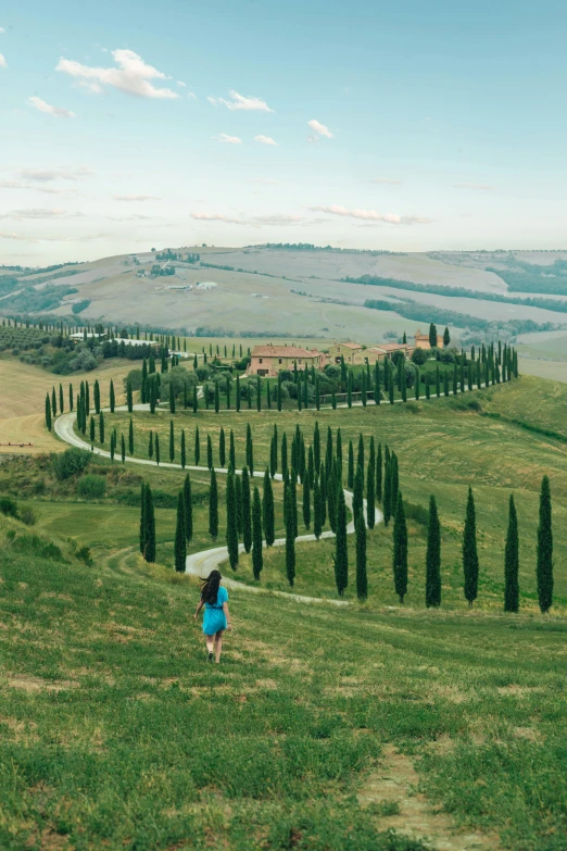 woman walking through rolling landscape near winding road