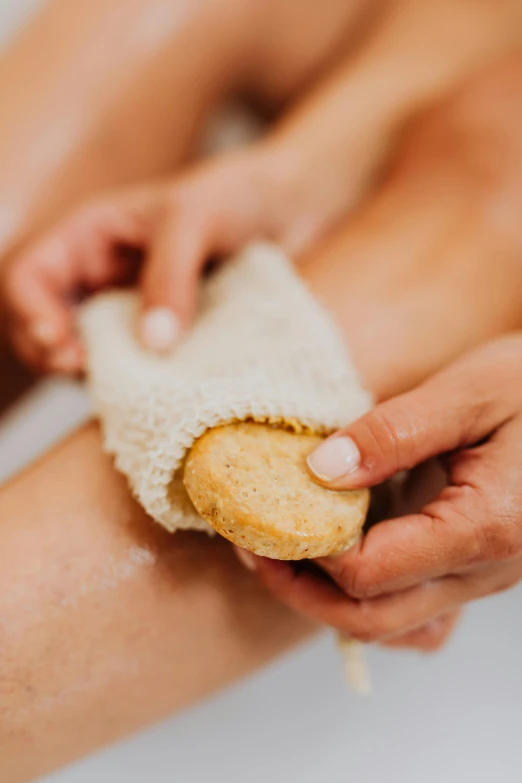 the person is sitting on the toilet holding onto a piece of bread