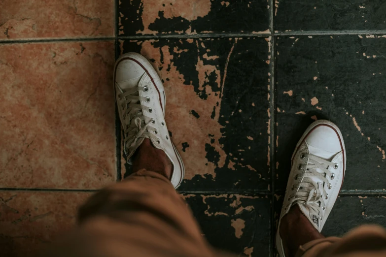 someone standing against a wall wearing tennis shoes