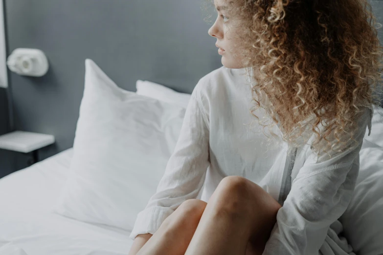 a woman sitting on top of a white bed