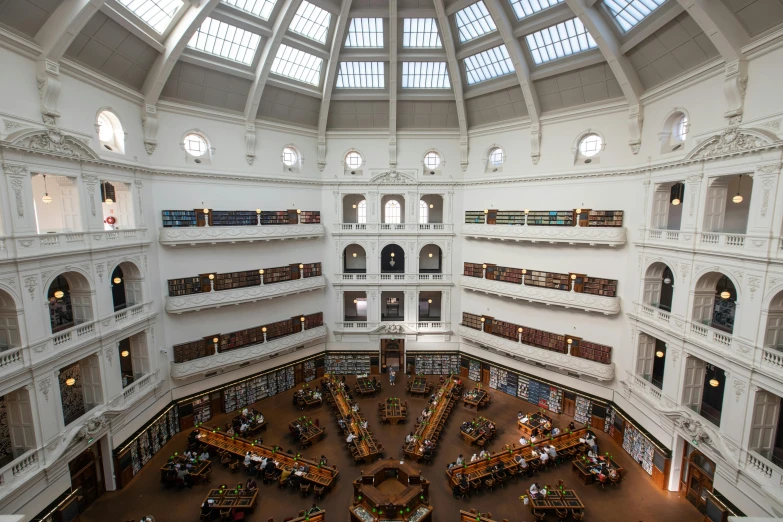 a large open area in a building has multiple levels and many bookshelves