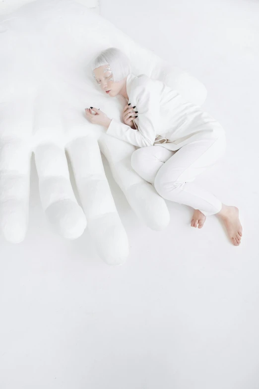 a white - skinned woman laying on her stomach and holding an arm on the white fluffy surface