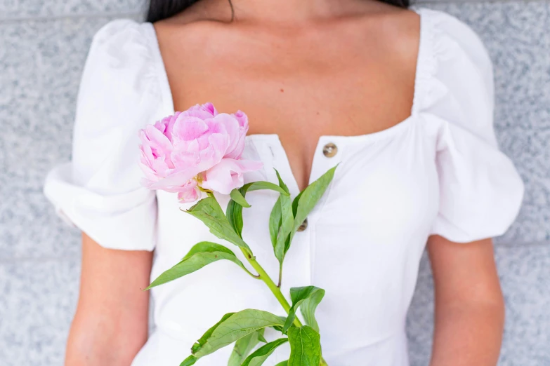 the woman holds a pink flower in her hand