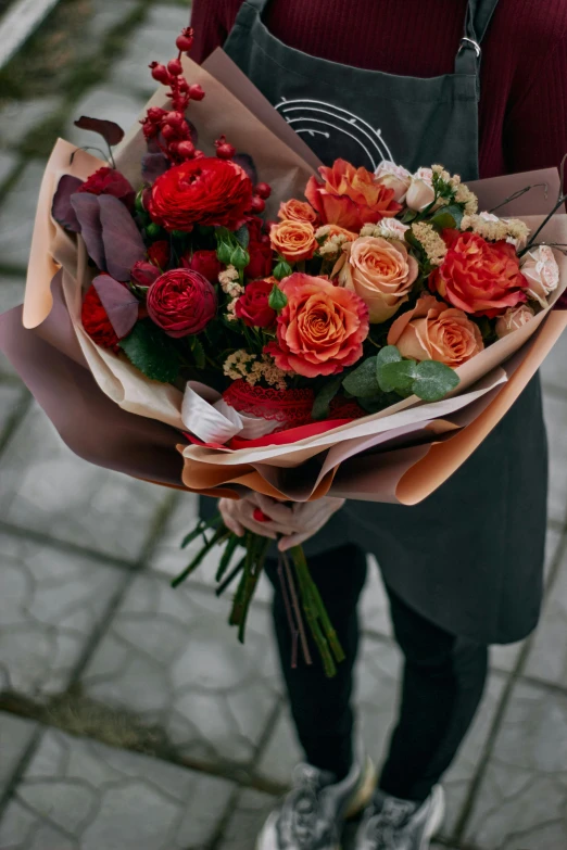 someone is holding up bouquet of flowers on the sidewalk