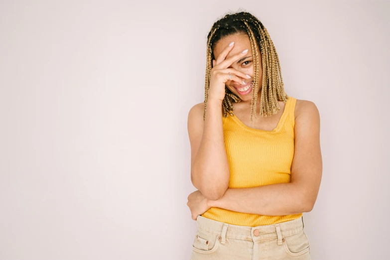 a woman is covering her eyes and looking into the camera