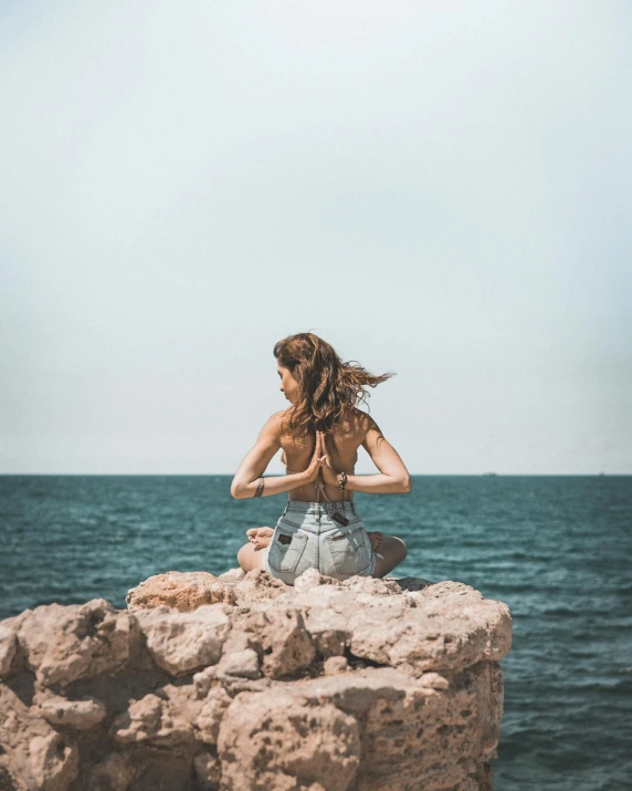 a  sitting on rocks facing the ocean