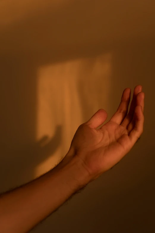 the light is casting a shadow of the hand and the wall